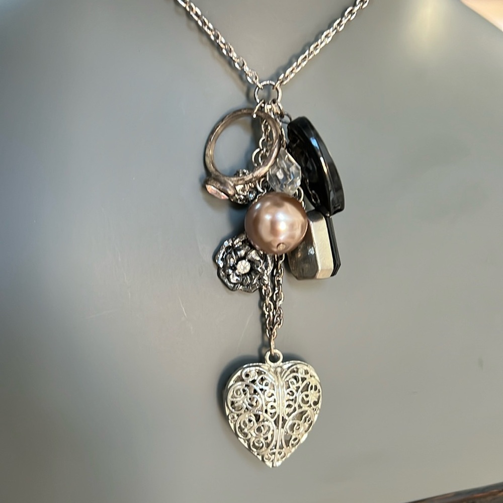 Long silver toned necklace with 8 charms in black and silver heart bead ring